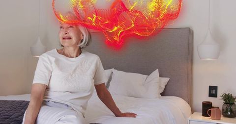 Senior woman relaxing on bed holding mug with glowing abstract mesh representing brain