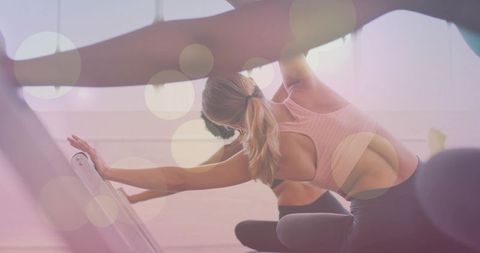 Blonde woman stretching on Pilates chair in soft studio light for fitness and flexibility