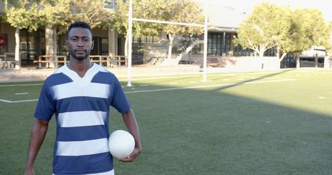 Rugby Player Holding Ball on Sunny Outdoor Field