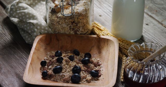 A wooden bowl contains oatmeal topped with blueberries, accompanied by a jar of honey and a bottle of milk, with copy space. The rustic setting suggests a wholesome and nutritious breakfast theme.