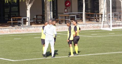 Youth soccer team listening to coach on sunny field