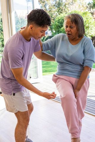 Elderly woman exercising with support from young man