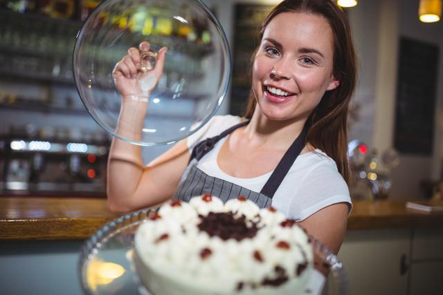 Portrait of smiling waitress holding a plate of cake in cafe