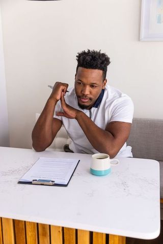 African american man reviewing documents at marble table holding pen and coffee mug