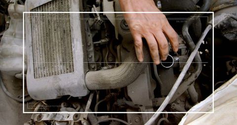 Mechanic inspecting engine bay with bare hand touching coolant hose and intercooler