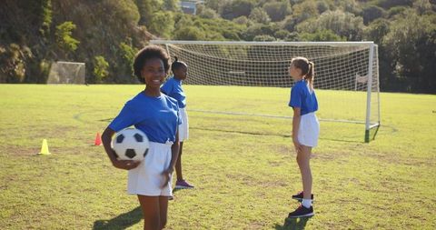 Diverse Girls Practicing Soccer Outdoors with Ball and Goal Posts
