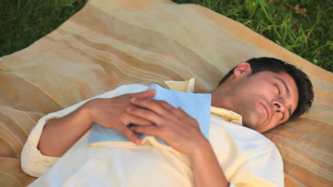 Man Relaxing with Book on Grass During Outdoor Nap