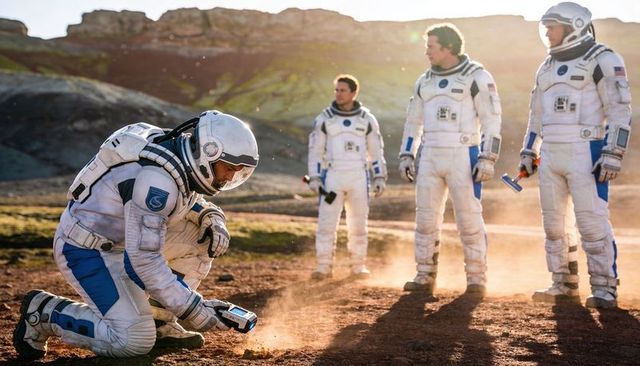 Planetary Science Team Kneeling Astronaut Scanning Red Plain While Crew Observing Tools