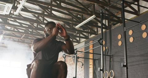Athletic man performing plyometric box jump in industrial gym