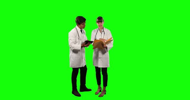 Two medical professionals in lab coats are consulting documents against a green screen background, making the image adaptable for various settings. Useful for healthcare presentations, medical training materials, advertisements, or any project requiring customized backgrounds.