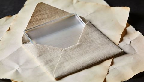 Linen Envelope Holding Clear Glass Block on Aged Parchment with Warm Patina