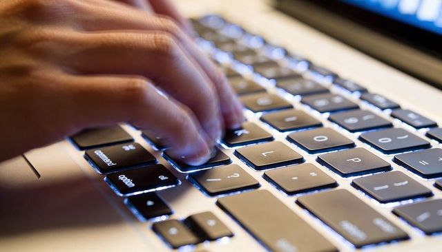 Hands Typing on Backlit Laptop Keyboard with Blue Night Glow