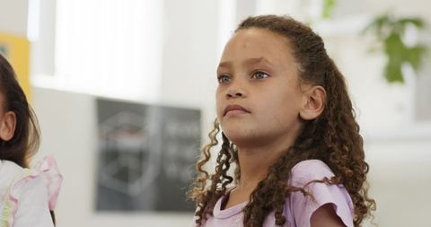 Curious african american schoolgirl looking up in classroom, student learning moment
