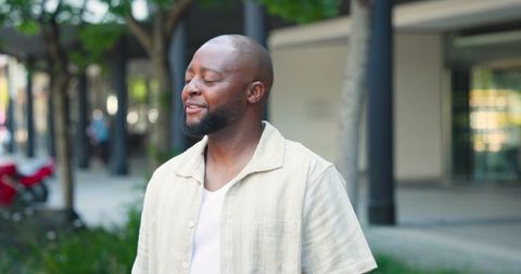 Relaxed african american man standing with eyes closed on city sidewalk enjoying moment