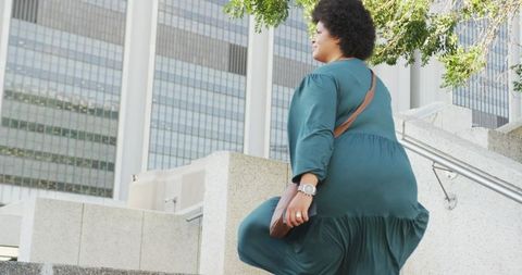 Confident plus size woman climbing city stairs with smartphone