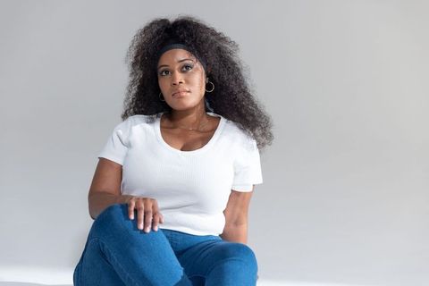 African american woman sitting on floor in white top and blue jeans, relaxed portrait