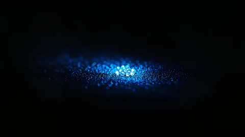 Pulsing Blue Bead Cluster Emitting Luminous Glow on Dark Surface with Bokeh Trail