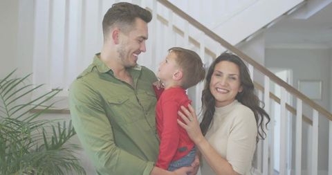Young family sharing joyful moment at home with father holding son on staircase