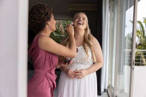 Bride Laughing with Makeup Artist Before Wedding Ceremony