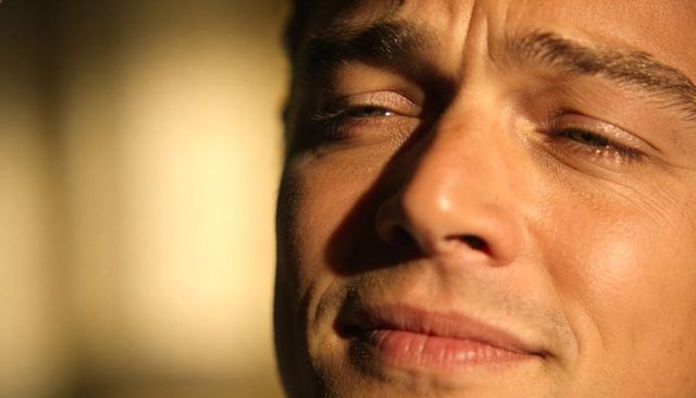 Sunlit closeup smiling man squinting with warm window glow
