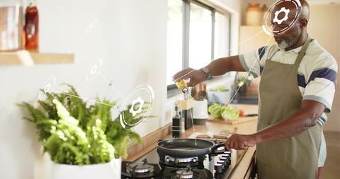 Senior man pouring oil into frying pan in bright home kitchen with smart ui overlay