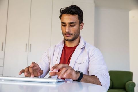 Focused asian man typing at home office desk