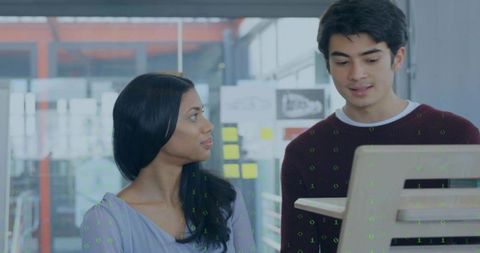 Collaborating colleagues reviewing laptop screen with sticky notes and prototype sketches