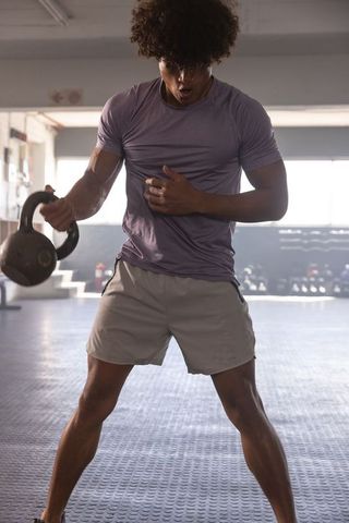Athlete swinging kettlebell in industrial gym during intense functional strength session