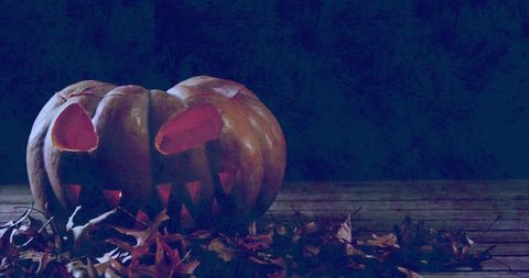 Spooky Halloween Jack-o'-Lantern Glowing on Leafy Table