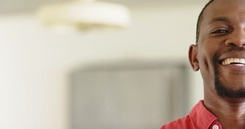 Closeup smiling african american man wearing red shirt at home with warm beige background