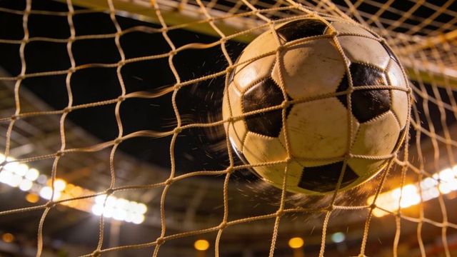 Soccer ball striking goal net under stadium lights during night match action and victory