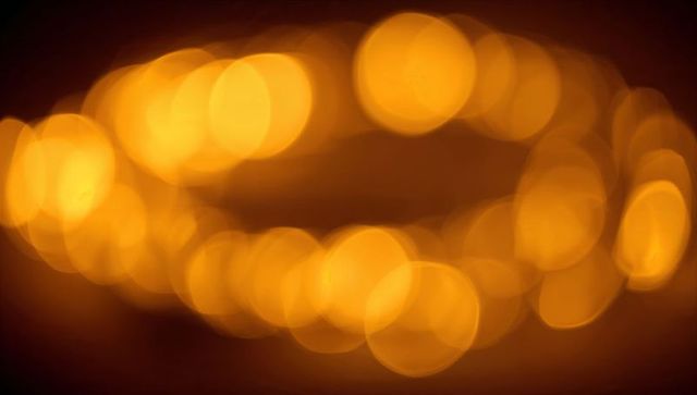 Warm golden bokeh lights forming soft horizontal arc, glowing orbs background for design