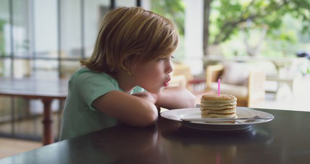 Young Boy Blowing Candle on Pancake Stack at Breakfast - Download Free Stock Images Pikwizard.com