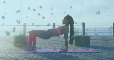 elegant shot of a woman practicing yoga on a seaside promenade, depicted with a digital network overlay. this conveys themes of technology integration in fitness routines. useful for content on modern workout innovations, seaside fitness styles, and digital health trends.