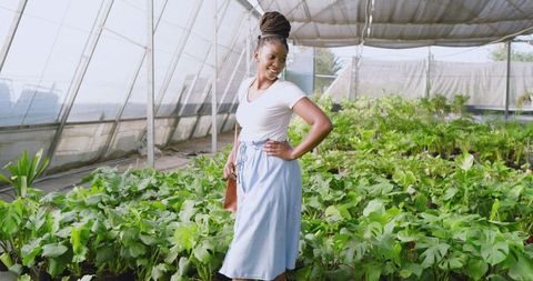 Smiling Woman Enjoying Greenhouse Filled with Lush Plants