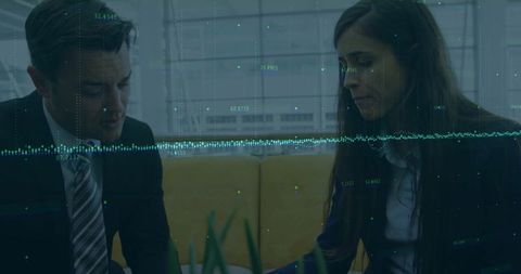 Colleagues Collaborating Over Digital Data in Modern Office Lounge