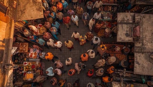 Overhead crowd walking through bustling indian bazaar, vendors selling fruit and textiles