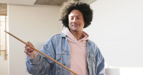 African american man holding pool cue in bright modern interior wearing denim jacket