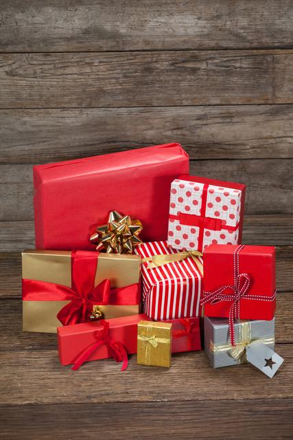 Perfect for holiday season promotions, Christmas event invitations, holiday shopping ads, or festive blog posts. The image features beautifully wrapped gift boxes of various sizes in red and gold colors, placed on a rustic wooden table, ideal for conveying a warm and festive holiday spirit.
