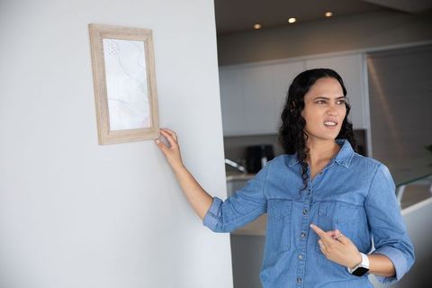 Woman in denim shirt dun, pointing wooden frame indignantly