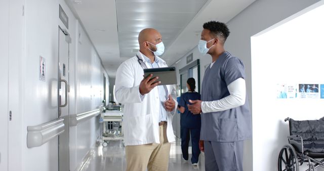 Medical professionals discussing in hospital hallway wearing masks - Download Free Stock Images Pikwizard.com