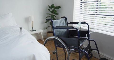 Sunlit accessible bedroom with wheelchair beside bed, minimalist cozy home care interior serene