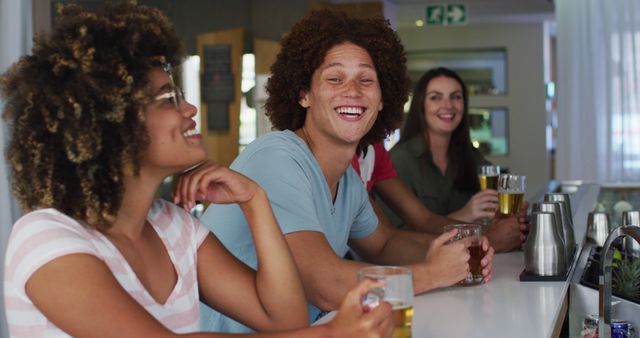 Diverse group of happy friends drinking beers and smiling at a bar. leisure time out socialising.