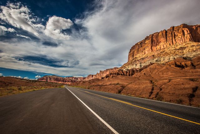 Empty road cutting through dramatic red rocky desert landscape - Download Free Stock Photos Pikwizard.com