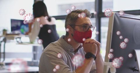 Masked professional using computer in office amid covid-19 concept