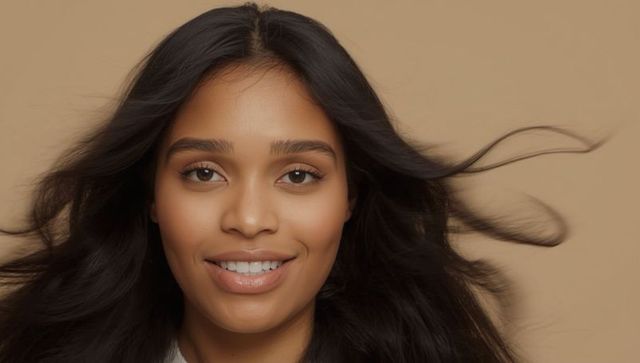 Smiling south asian woman with flowing hair on beige background