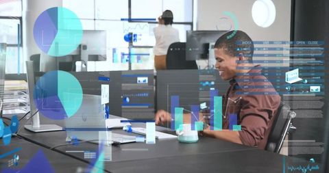 Smiling data analyst typing at modern open-plan desk with interactive data visualizations