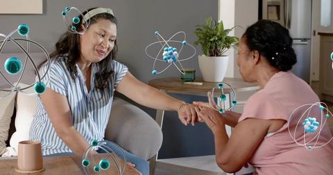 Two women holding hands sharing comfort and connection at home with atomic overlays