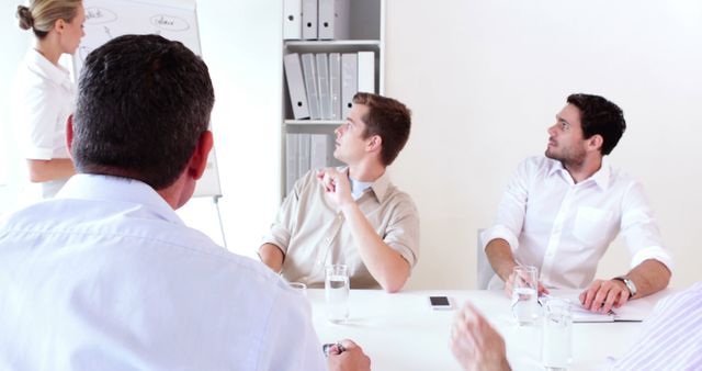 Team of male and female professionals in midst of collaborative brainstorming session. Group focused on presenting business ideas using whiteboard in modern, minimalistic office. Useful for business, teamwork, collaboration, professional presentation concepts, workplace productivity illustrations.