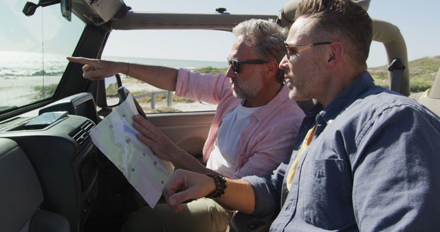 Two Men Navigating with Map on Road Trip in Convertible near Coast - Download Free Stock Images Pikwizard.com